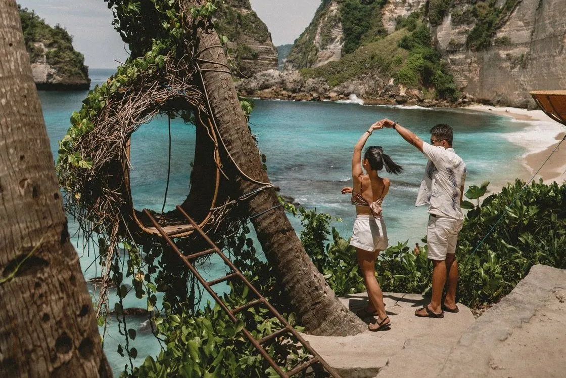 A couple dancing beside the tree swing above Diamond Beach, Nusa Penida