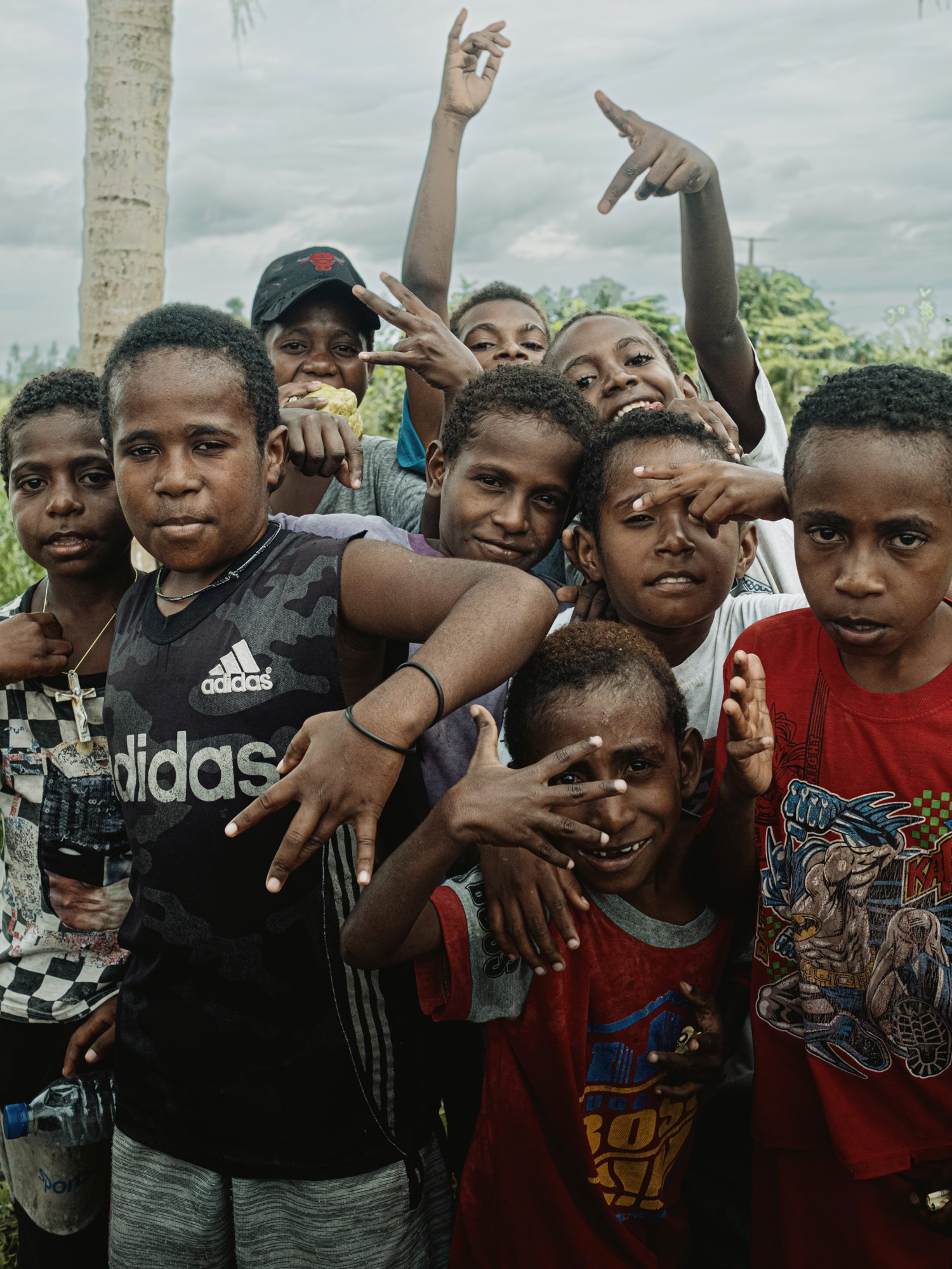 A group of children raise their arms, laughing, by the river