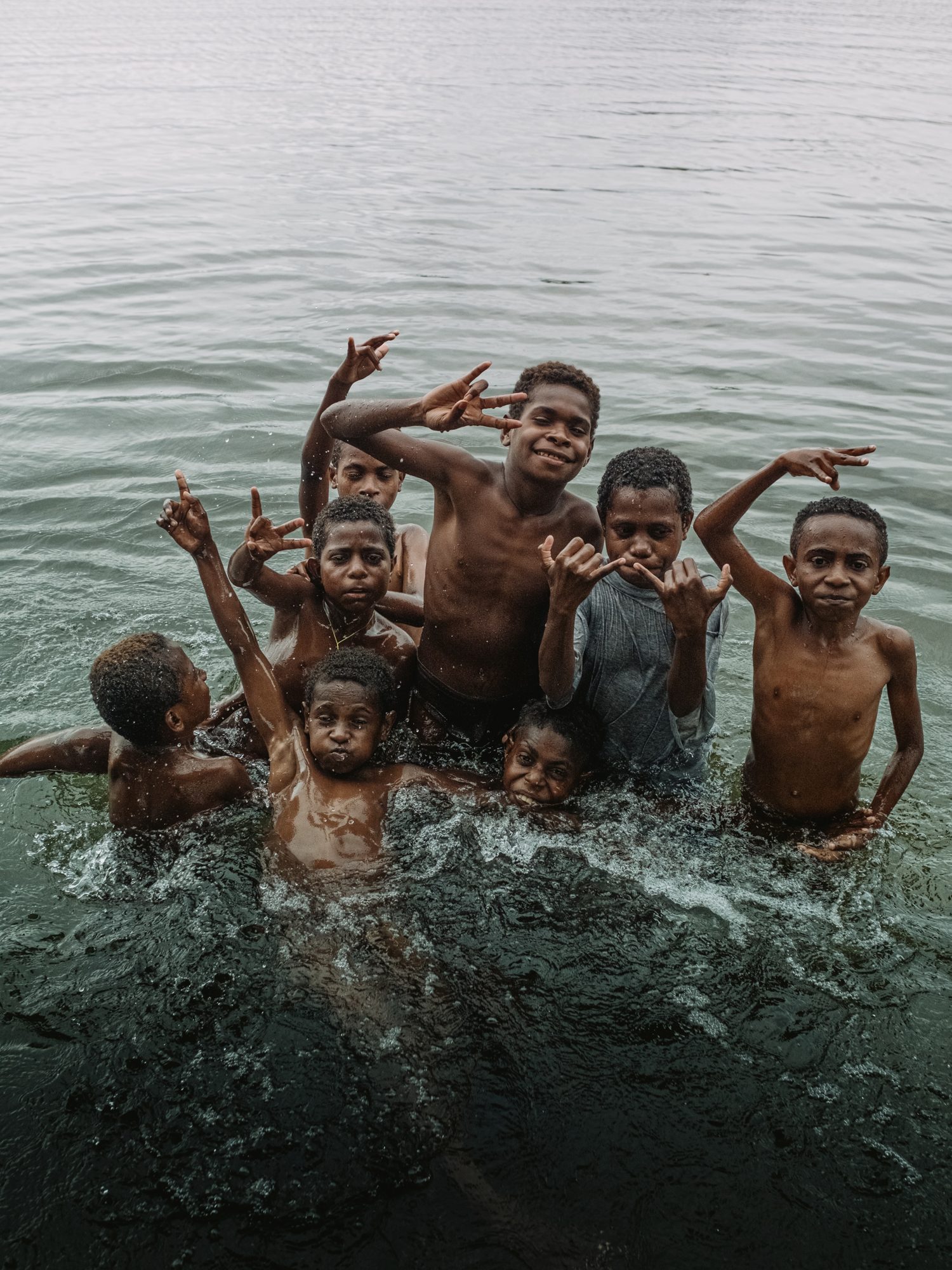 Children wave from the river, arms raised